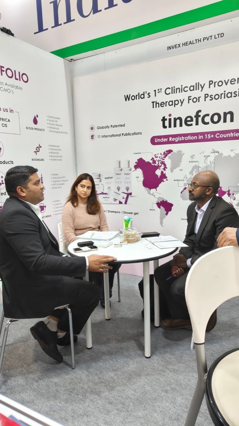 A meeting around a table at CPHI Milan, in front of a Tinefcon psoriasis-therapy banner